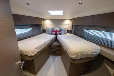 Luxurious 2022 Princess V50 yacht cabin with twin beds and Union Jack pillow.