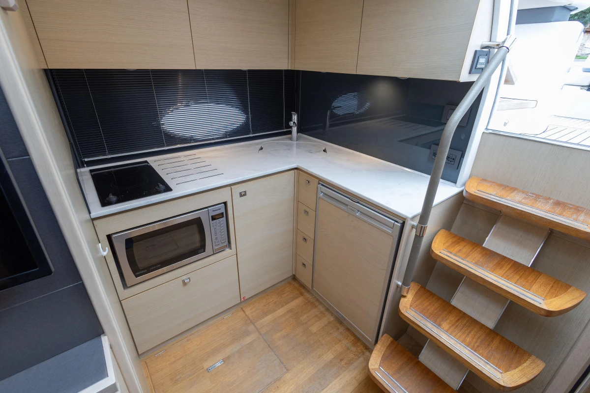 Modern kitchen in 2016 Princess V39 yacht with microwave, stove, and wooden stairs.