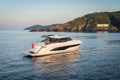 Luxurious 2025 Princess V55 yacht cruising near scenic coastline at sunset.