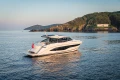 Luxurious 2025 Princess V55 yacht cruising near scenic coastline at sunset.