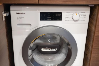 Miele WT1 Excellence washing machine installed in wooden cabinet.