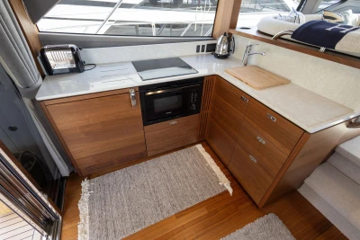 Modern kitchen interior on 2024 Princess F50 yacht with wooden cabinetry and appliances.