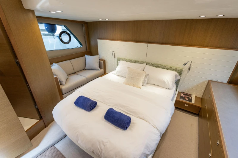 Luxurious bedroom interior of 2017 Princess V48 Open yacht with cozy bed and seating area.