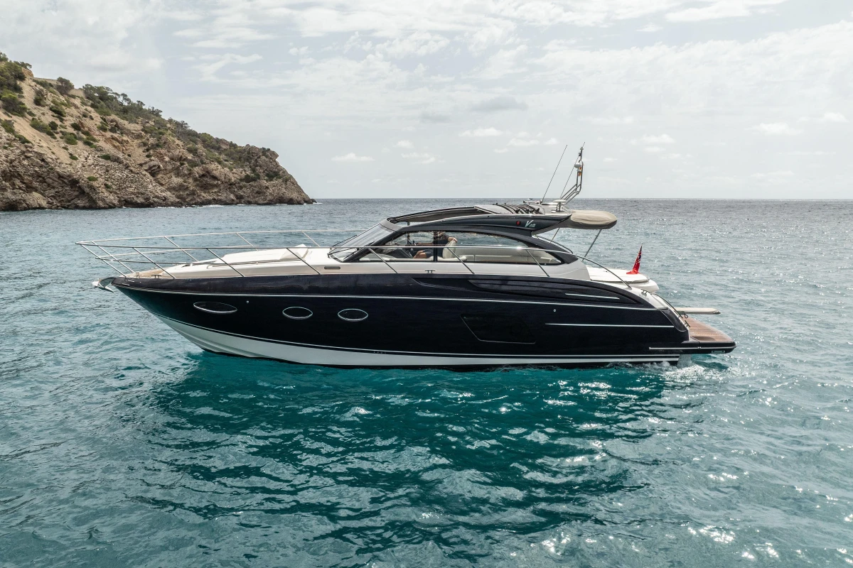 2017 Princess V48 Open yacht on clear blue water near rocky coastline.