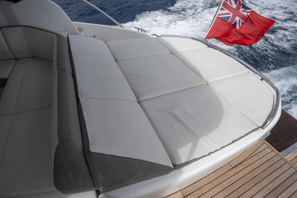 2017 Princess V48 Open yacht with cushioned deck and flag, cruising on the ocean.