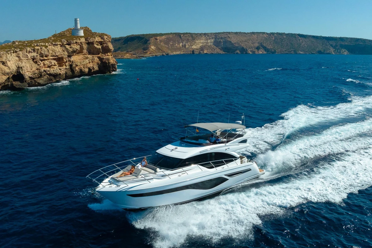 Luxury Princess F55 yacht cruising near rocky coastline and lighthouse, 2023 model.