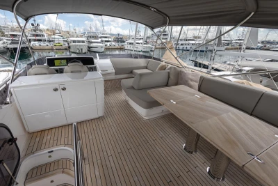 Luxurious 2023 Princess F55 yacht deck with seating and table, docked at marina.