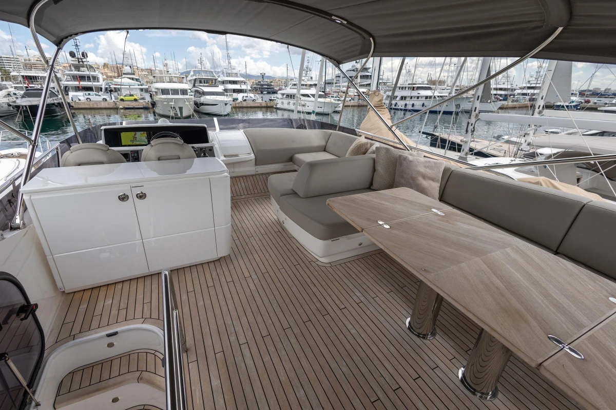 Luxurious 2023 Princess F55 yacht deck with seating and table, docked at marina.