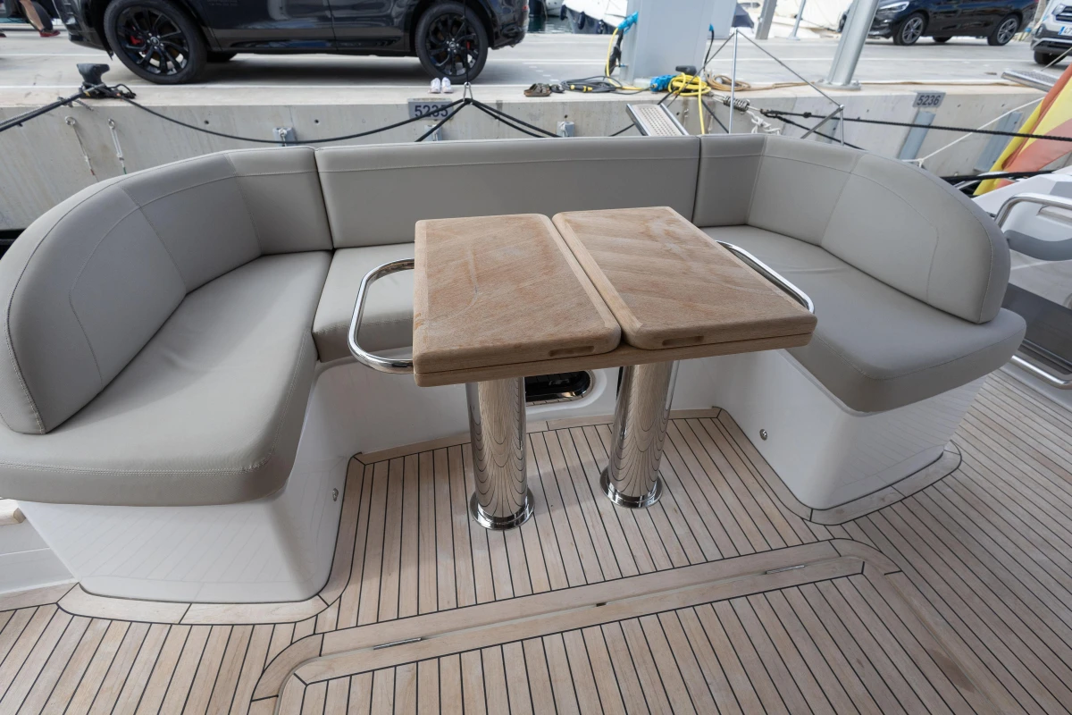 Luxurious seating area on 2023 Princess F55 yacht with wooden table and cushioned benches.
