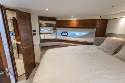 Luxurious cabin interior of 2023 Princess F55 yacht with elegant wood finishes and cozy bedding.