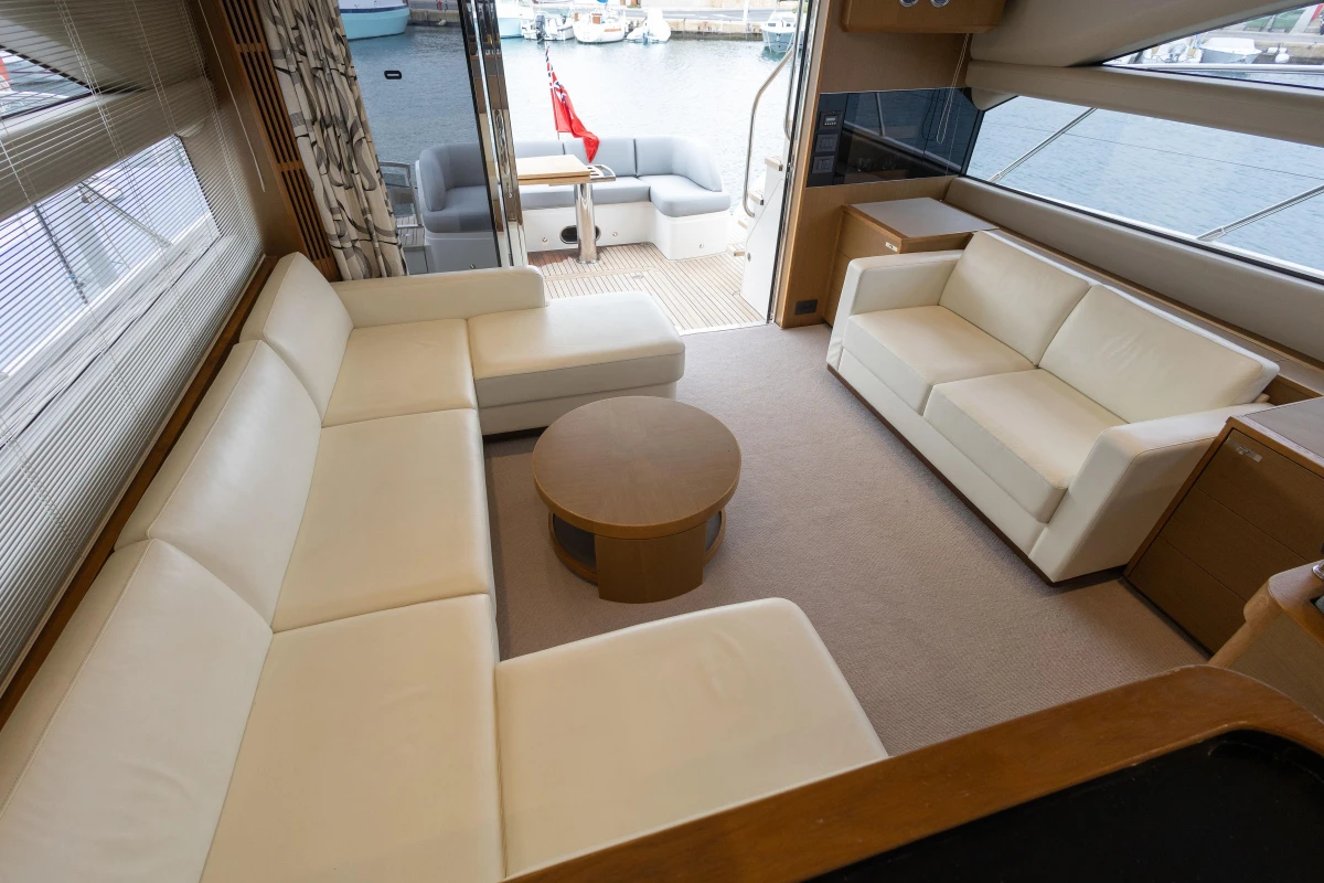 Luxurious interior of 2014 Princess 56 yacht with cream sofas and round table.