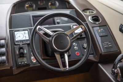 Steering wheel and dashboard of a 2014 Princess 56 yacht, featuring modern controls and gauges.