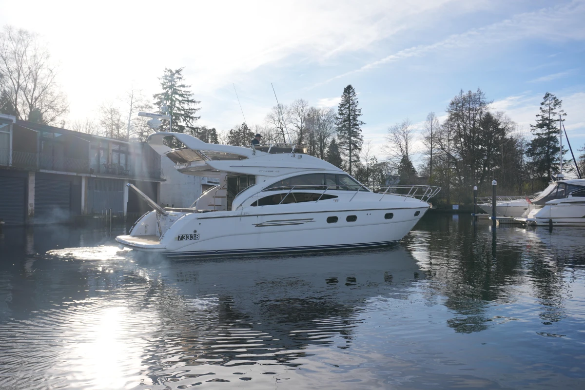 2006 Princess 42 Flybridge Motor Yacht on calm water, surrounded by trees and buildings.