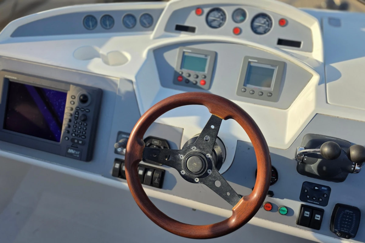 Control panel of 2006 Princess 42 Flybridge Motor Yacht with wooden steering wheel.