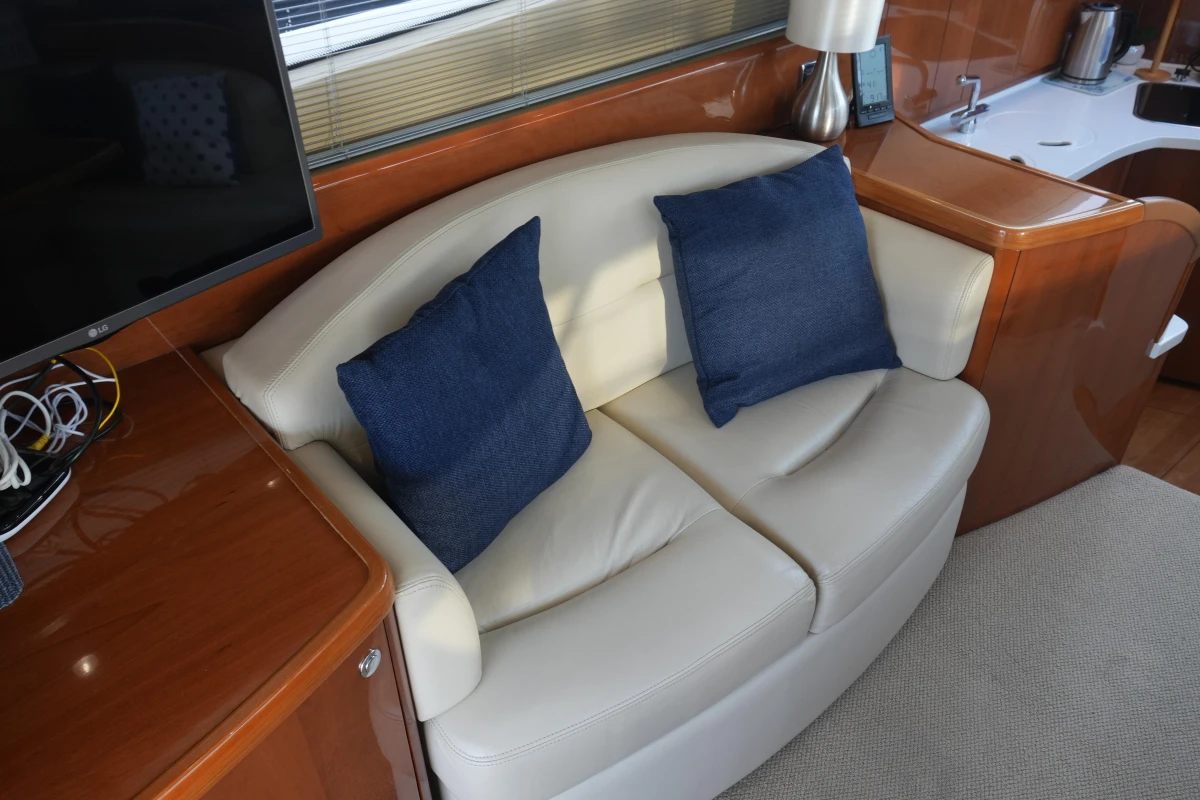 Luxurious interior of 2006 Princess 42 Flybridge Motor Yacht with cream sofa and blue cushions.