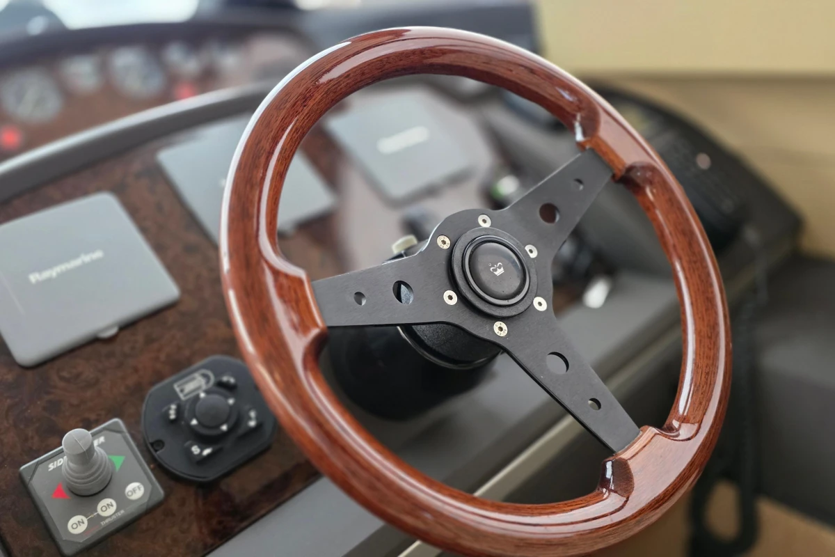Steering wheel of a 2006 Princess 42 Flybridge Motor Yacht, featuring wood and metal design.