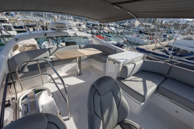Luxurious 2023 Princess F50 yacht interior with seating and table, docked at marina.