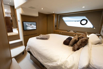 Luxurious bedroom interior of 2014 Princess V52 yacht with modern decor and large window.