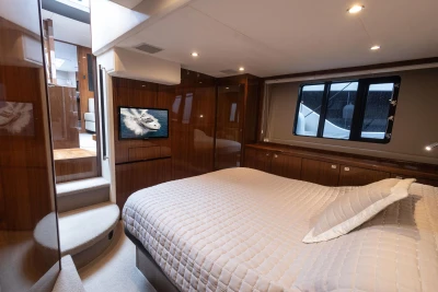 Luxurious bedroom interior of 2012 Princess V52 yacht with elegant wood finishes and cozy bedding.