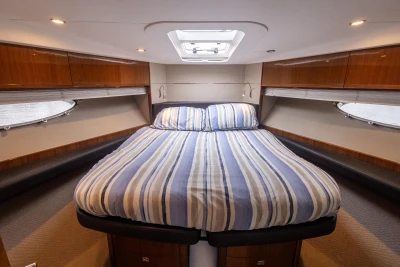 Luxurious cabin interior of 2012 Princess V52 yacht with striped bedding.