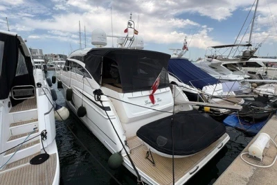 2013 Princess V52 yacht docked at marina, surrounded by other boats under cloudy sky.