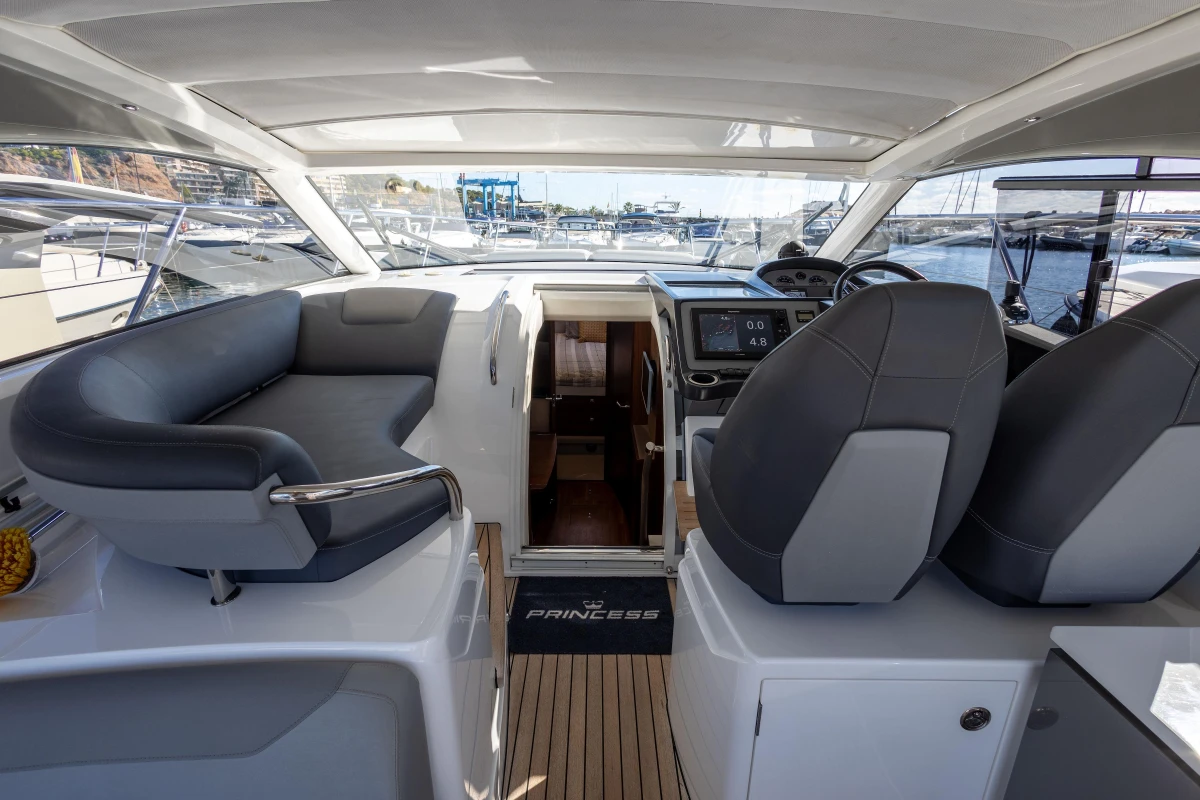 2017 Princess V40 yacht interior with helm, seating, and marina view.