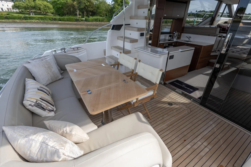 The image shows the deck of a 2022 Princess F55 yacht with elegant seating and a table.