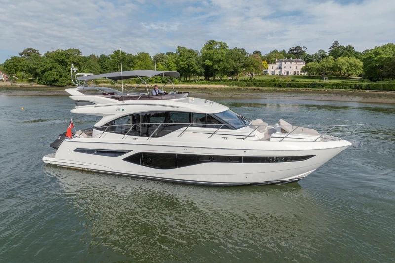 The 2022 Princess F55 is an elegant motor yacht on calm waters, surrounded by lush greenery.