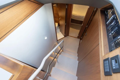 Staircase in a yacht with wood paneling, leading to cabins with closed doors.