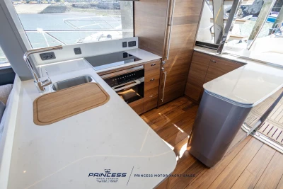 Modern kitchen interior of 2023 Princess S72 yacht with sleek wood and white finishes.