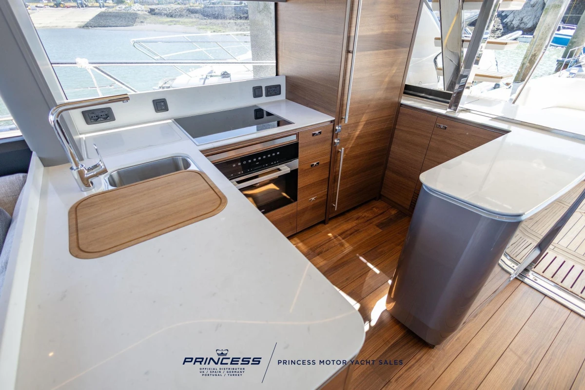 Modern kitchen interior of 2023 Princess S72 yacht with sleek wood and white finishes.