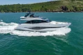 2023 Princess S72 yacht cruising on blue ocean near lush green coastline.