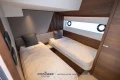 Luxurious 2023 Princess S72 yacht cabin with twin beds and modern wood paneling.