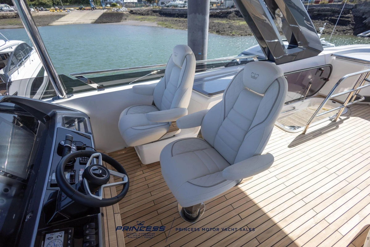 Luxury helm seats on 2023 Princess S72 yacht with sleek dashboard and waterfront view.