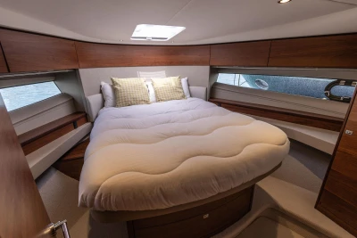 Luxurious 2019 Princess F50 yacht bedroom with elegant wood finishes and cozy bedding.