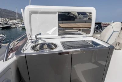 Outdoor kitchen on 2019 Princess F50 yacht with sink and grill, docked at marina.