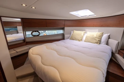 Luxurious 2019 Princess F50 yacht bedroom with elegant wood accents and plush bedding.