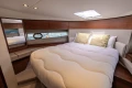Luxurious 2019 Princess F50 yacht bedroom with elegant wood accents and plush bedding.