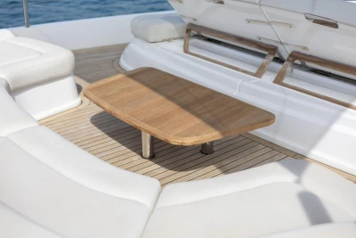 Luxurious seating area on 2021 Princess Y72 yacht with wooden table and white cushions.