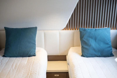 Twin beds with blue cushions in a 2021 Princess Y72 yacht cabin.