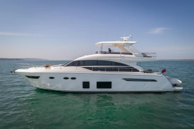 A luxurious white yacht on calm water under a clear sky.