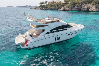 Luxurious 2010 Princess 50 yacht cruising in clear turquoise waters near rocky coastline.