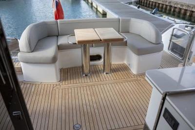 Luxurious 2022 Princess F55 yacht deck with seating and table, docked by the water.