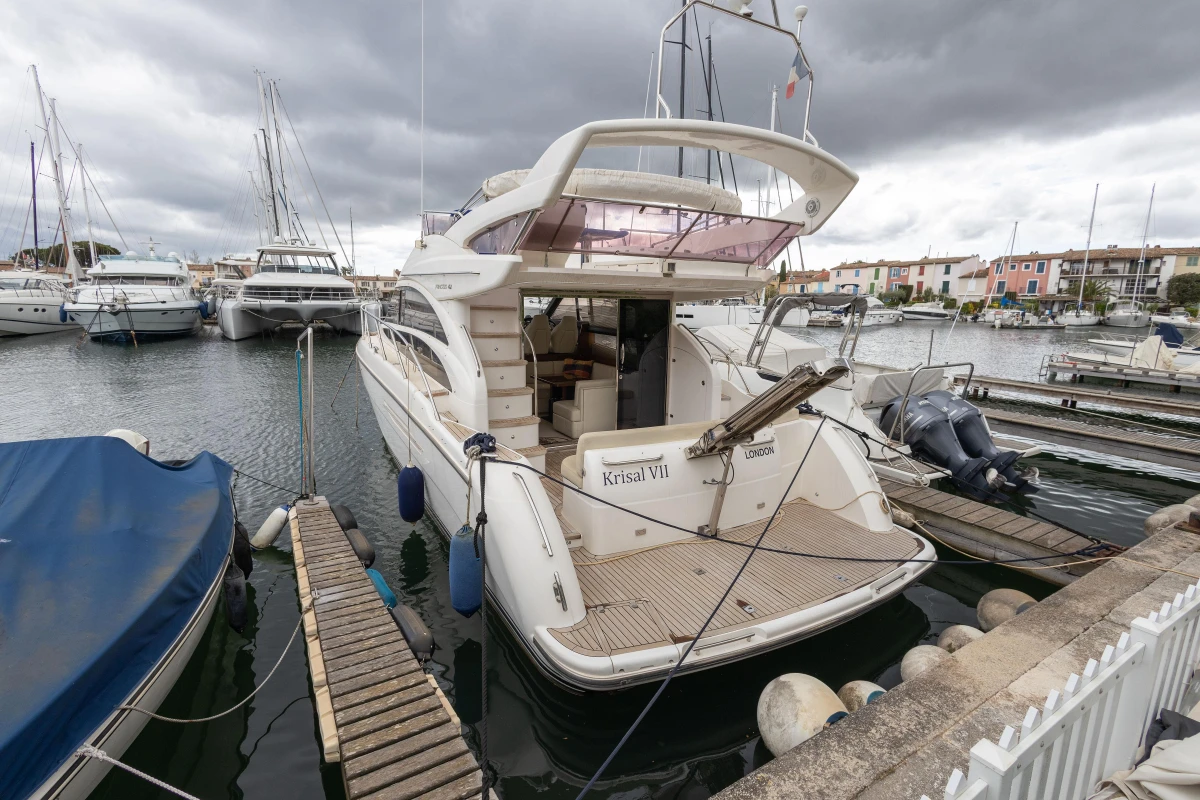 Luxury 2013 Princess 42 yacht docked in a marina under cloudy skies.