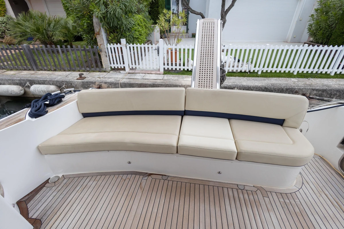 Curved beige seating on 2013 Princess 42 yacht deck, with wooden flooring.