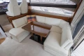 Luxurious interior of 2013 Princess 42 yacht with white leather seating and wooden table.