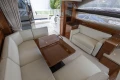 Luxurious interior of 2013 Princess 42 yacht with white leather seating and wooden accents.