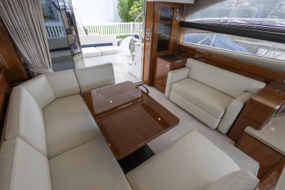Luxurious interior of 2013 Princess 42 yacht with white leather seating and wooden accents.