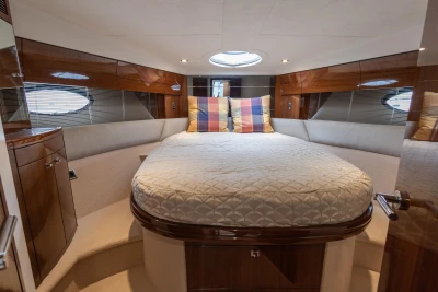 Luxurious cabin interior of 2013 Princess 42 yacht with cozy bed and elegant wood finishes.