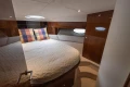 Luxurious cabin interior of 2013 Princess 42 yacht with cozy bedding and elegant wood finish.